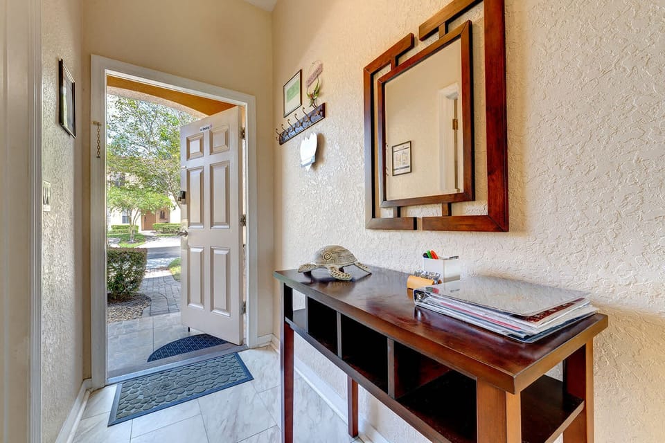 Entryway with a wooden console table and decorative mirror welcoming natural light.