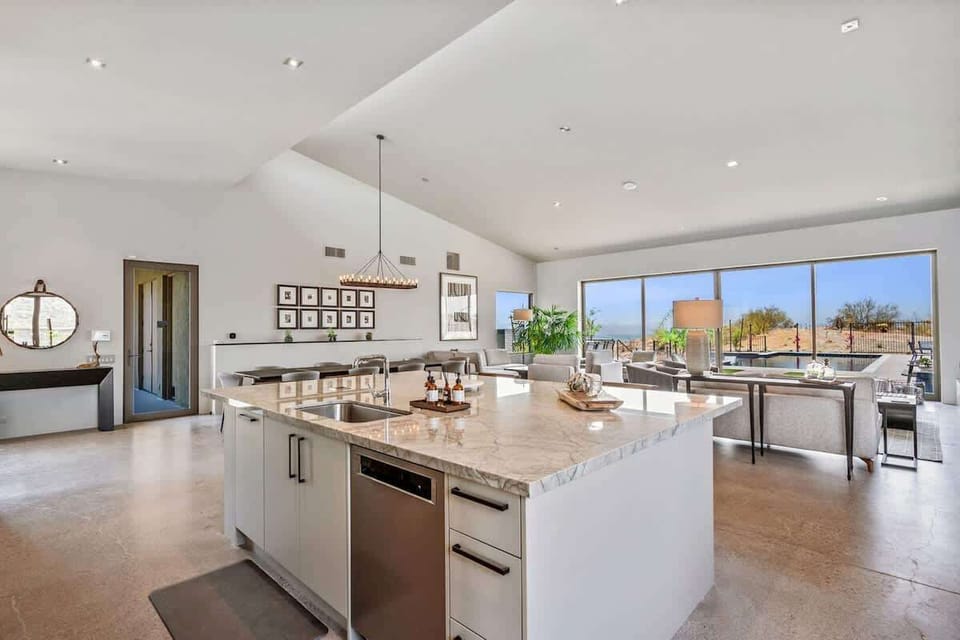 Fully equipped luxury kitchen stocked with all culinary essentials and features high-end stainless-steel appliances, a kitchen island, a dining table, and a wet bar/coffee station.
