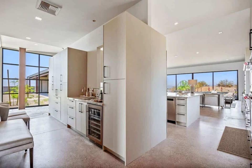 Fully equipped luxury kitchen stocked with all culinary essentials and features high-end stainless-steel appliances, a kitchen island, a dining table, and a wet bar/coffee station.