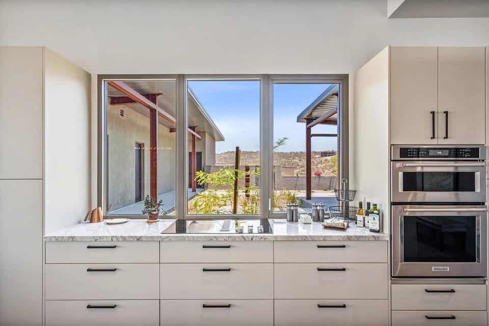 Fully equipped luxury kitchen stocked with all culinary essentials and features high-end stainless-steel appliances, a kitchen island, a dining table, and a wet bar/coffee station.