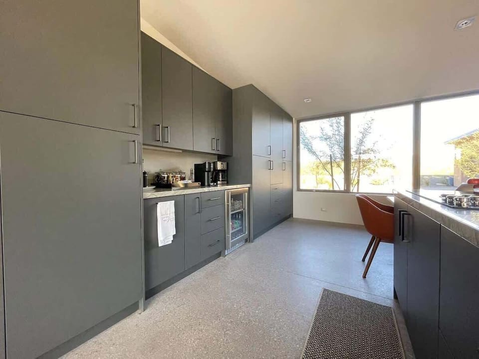 Fully equipped luxury kitchen stocked with all culinary essentials and features high-end stainless-steel appliances, a kitchen island, a breakfast table, and a wet bar / coffee station.