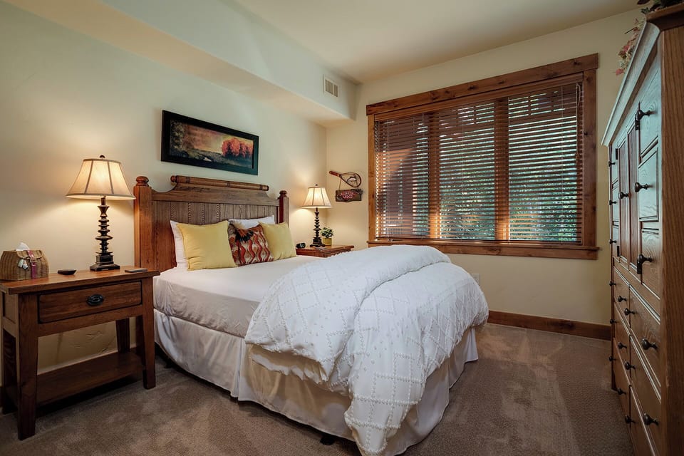 Sink into rustic elegance in your peaceful bedroom retreat, where warm wood details and soft linens create your perfect mountain getaway sanctuary.