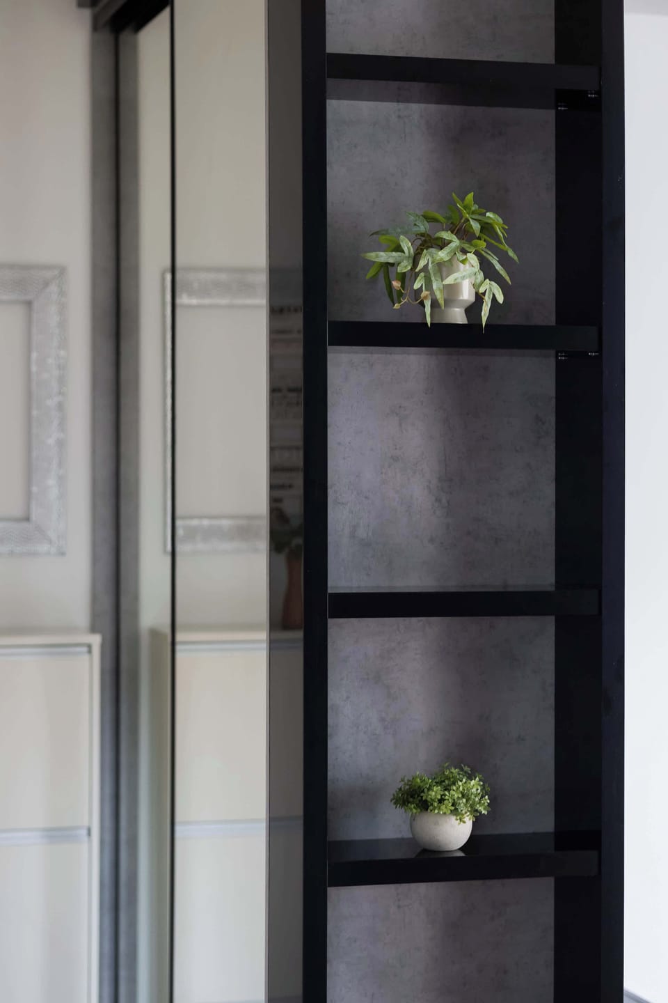 A narrow shelving unit with decorative plants and modern design.
