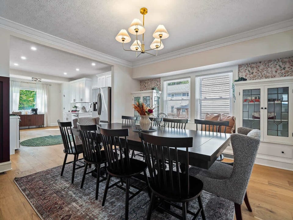 Spacious dining area framed by windows & chandelier, perfect for gathering around the table.