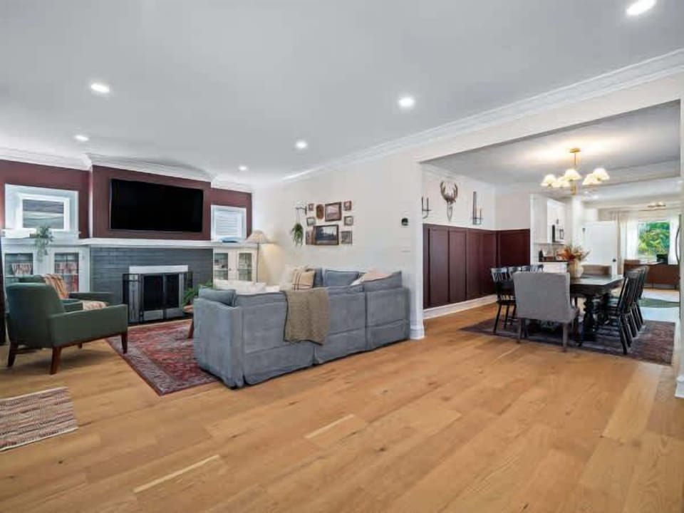 Airy living room w/ open layout, fireplace, & soft seating flowing into the dining area.