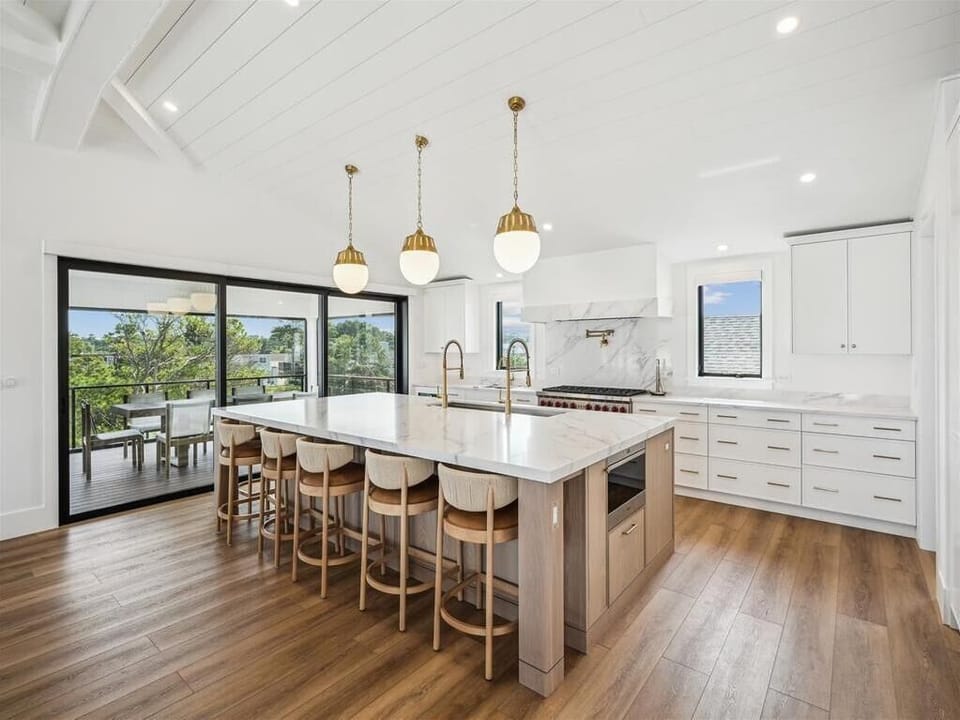 Showcasing a stylish layout, this kitchen offers breathtaking views from its large glass doors, combining modern charm with a seamless connection to outdoor dining.