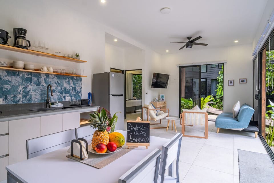 Open-concept living area with modern kitchen, dining space, and tropical garden views at Somnara Espuma de Mar, Playa Chiquita, Costa Rica