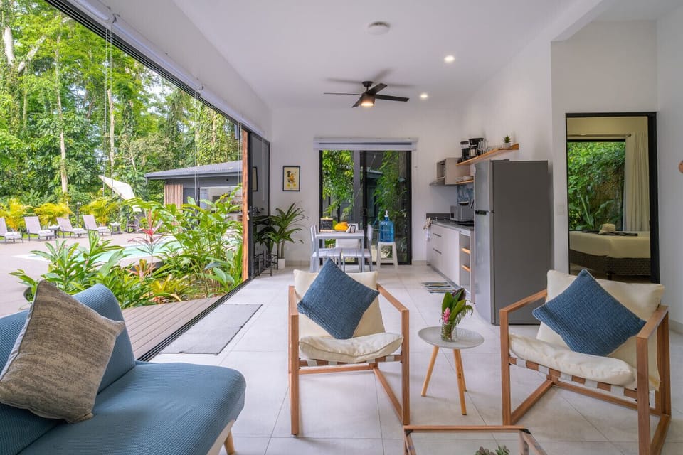 Bright open-plan living area with tropical garden views and modern kitchen at Somnara Espuma de Mar, Playa Chiquita, Costa Rica