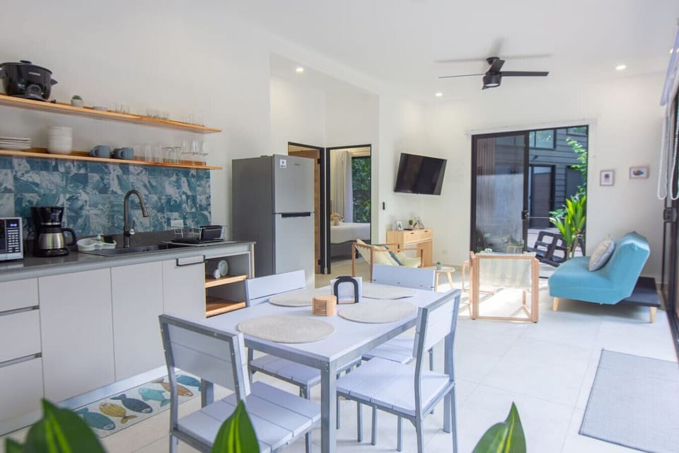 Bright open kitchen and living area with dining space and garden access at Somnara Espuma de Mar, Playa Chiquita, Costa Rica.