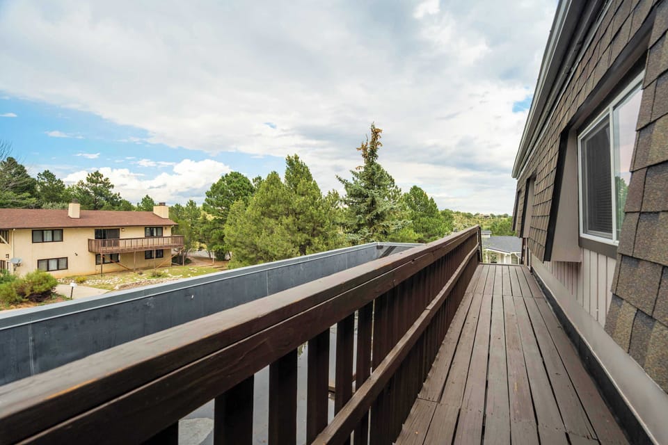 Upper-level balcony with wooden railing and wide views of the surrounding neighborhood and treetops. A quiet spot to step outside and take in the fresh air.