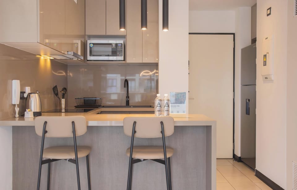 Modern kitchen with bar stools and built-in appliances.