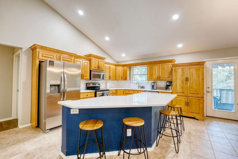 Your culinary space with this stunning kitchen featuring a chic blue island and beautiful wooden cabinets!