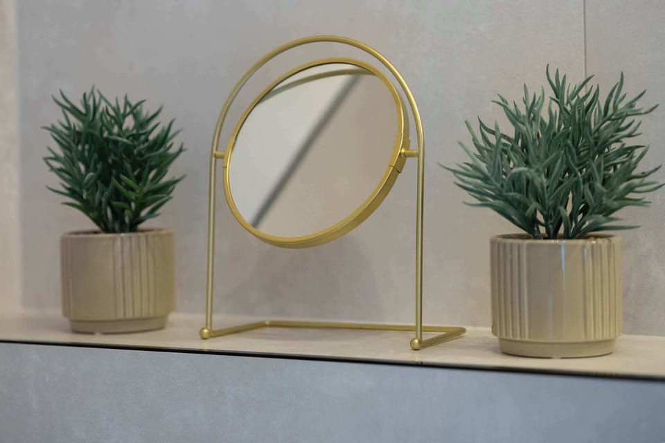 A stylish vanity with a round mirror and green plants serves as an elegant spot for morning self-care.
