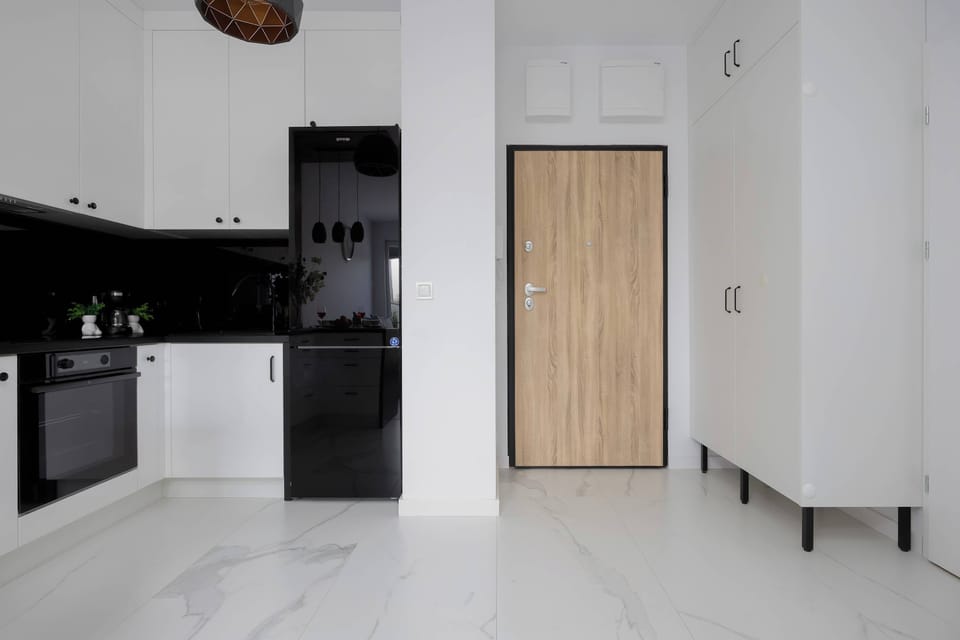The elegant entrance to the apartment opens into a black-and-white kitchen, emphasizing the modern character of the interior.