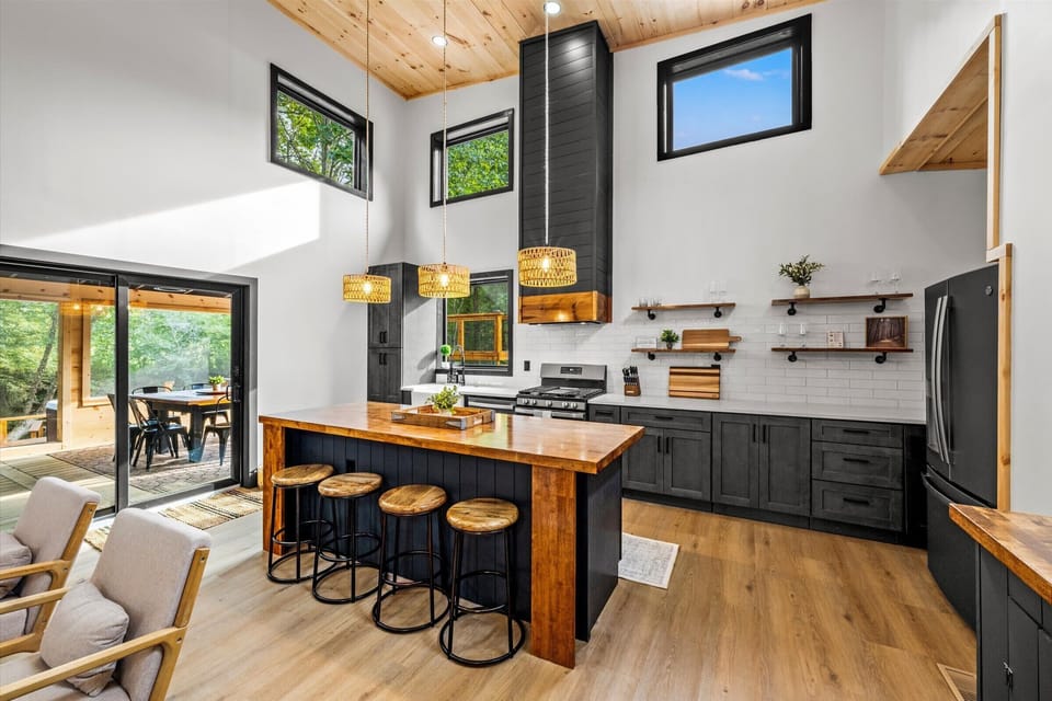 Open, modern kitchen with warm wood, bold black accents, and a 4-seat island.
