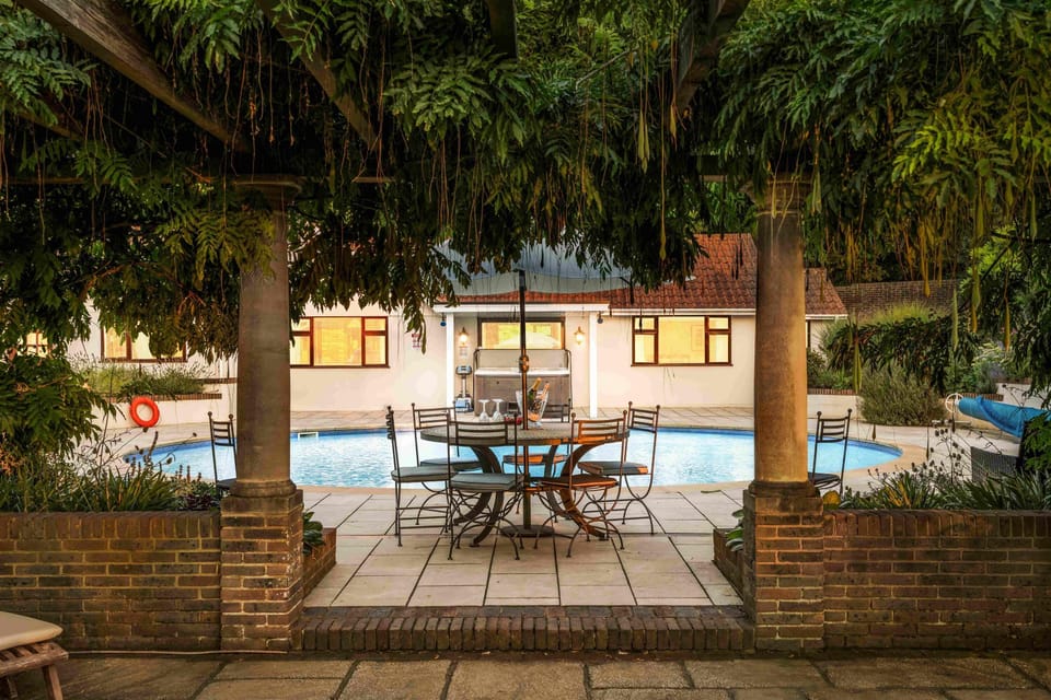 Elegant jacuzzi-style hot tub nestled within a garden terrace, accented by lush greenery and ornate outdoor seating