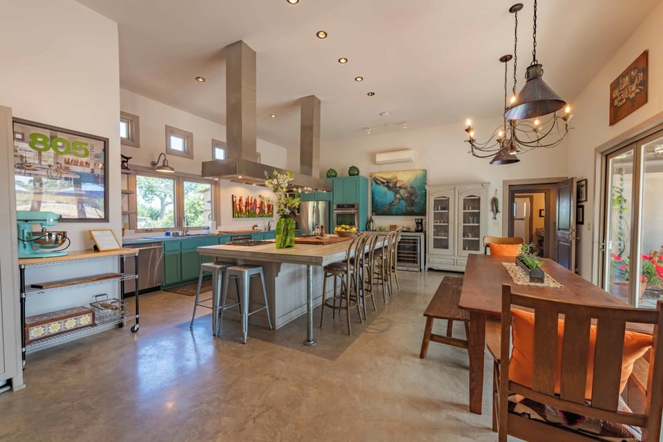 Gather around this chef's kitchen with vibrant turquoise cabinetry, spacious center island, and warm pendant lighting—your home base for delicious meals and memories together.