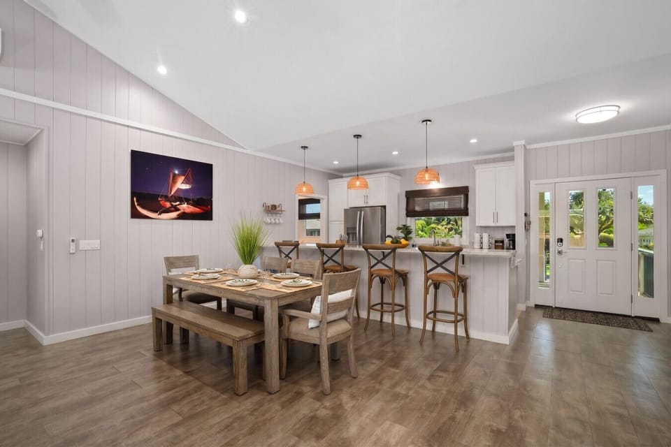 Main house dining area with large table, bar seating, and open-concept kitchen filled with natural light.