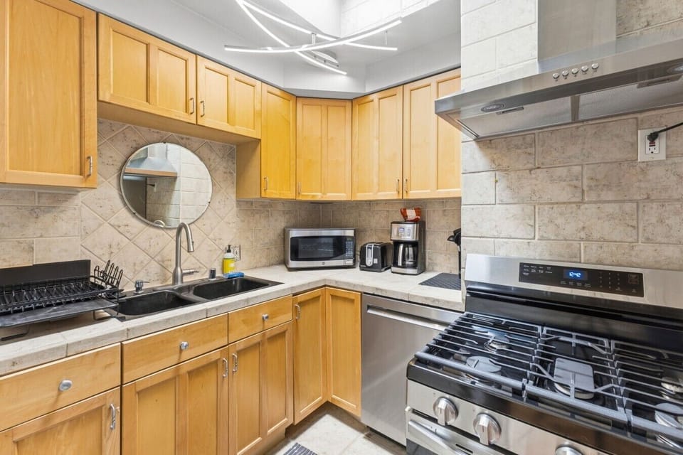 Fully equipped kitchen with warm wood cabinetry, a stainless steel gas range and oven, built-in dishwasher, and microwave.