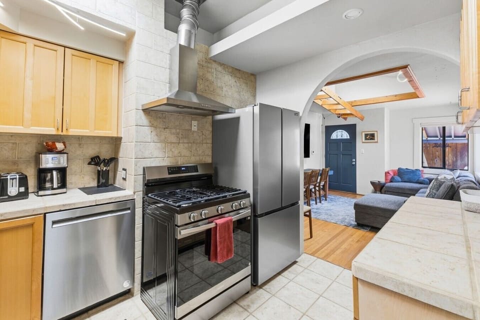 Fully equipped modern kitchen with stainless steel appliances, opening right into the warm and inviting living space.