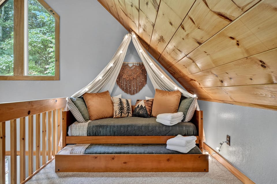 Cozy loft bedroom with serene forest view, perfect for relaxation.
