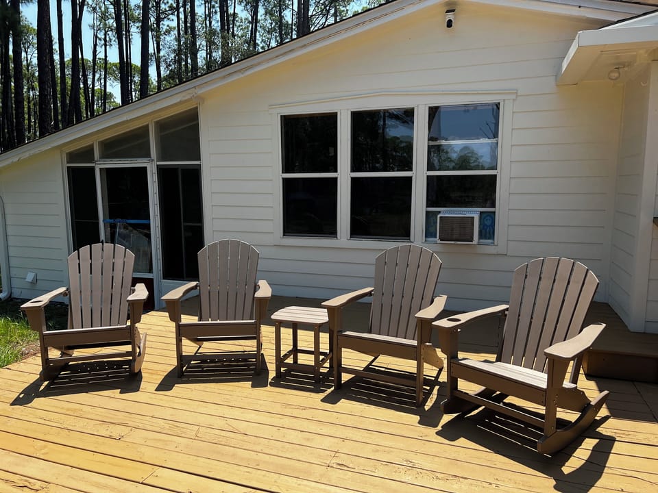 Two rocking and two still Adirondack chairs on the deck facing mullet pond
