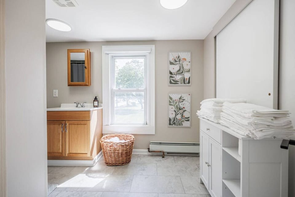 Modern bathroom with a bath tub, fresh towels, and essential toiletries. Designed for comfort and convenience, offering a clean and refreshing space to start or end your day.