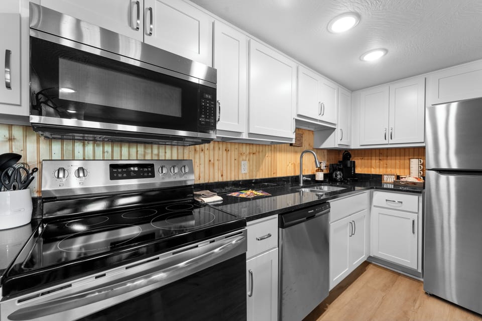 Another view of the kitchen shows black appliances and warm wood accents, blending style with functionality for a convenient stay.