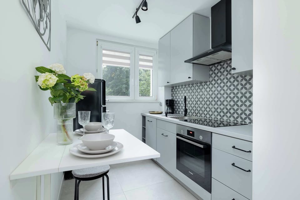 A kitchen corner with a small round table and chairs near the window. White and black accents dominate the interior.