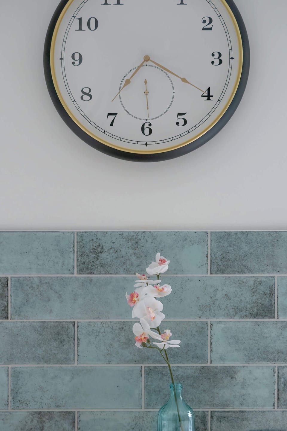 A stylish wall clock suspended above a green glaze is an elegant decorative accent in the kitchen.