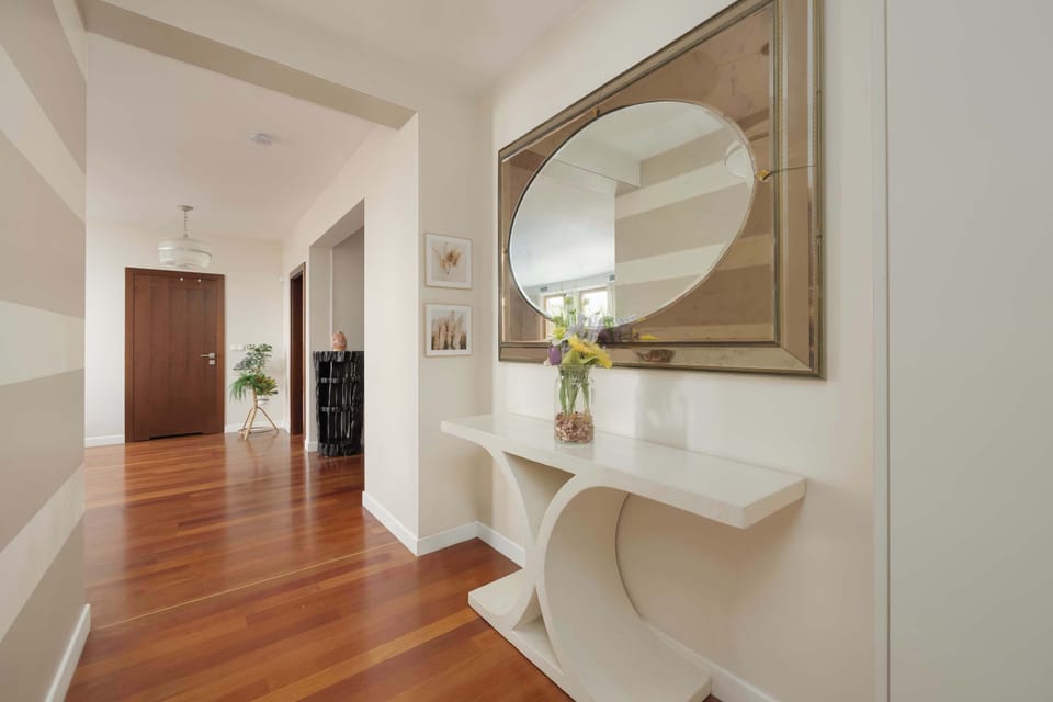 Spacious hallway with wooden floors and mirror.