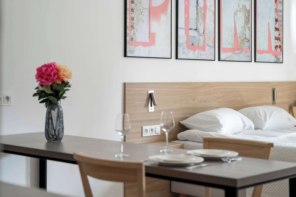 The kitchenette with wooden cabinets, a stove, and a small dining table nearby. Fresh flowers add a welcoming touch.