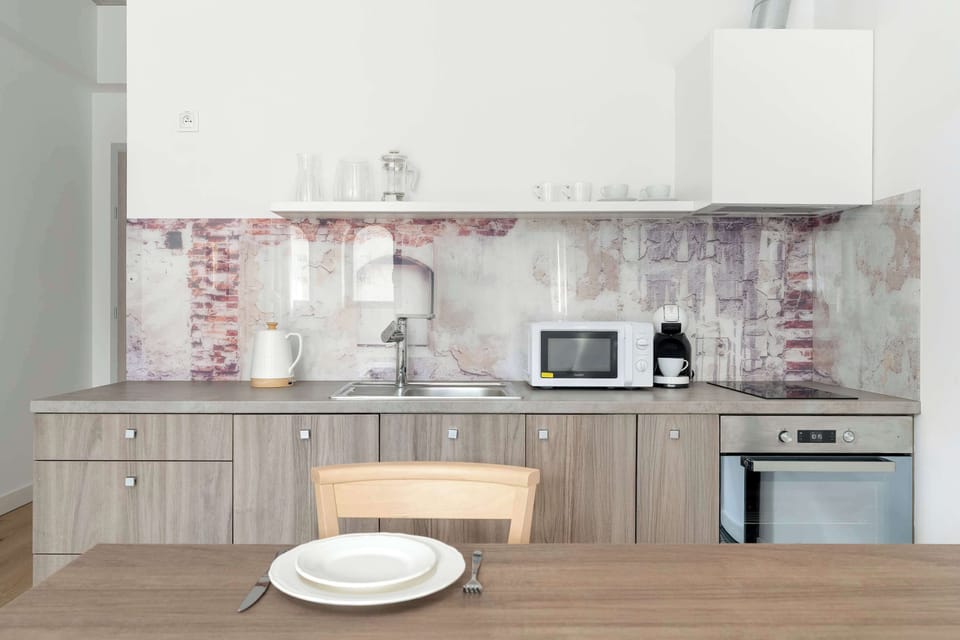 A closer view of the kitchenette, showing plates on the table and the countertop appliances. The design blends wood and modern finishes.