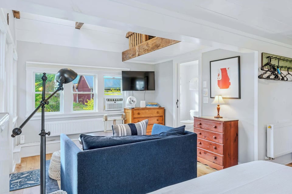 Living space from the bedroom with TV, vintage dresser, and natural light