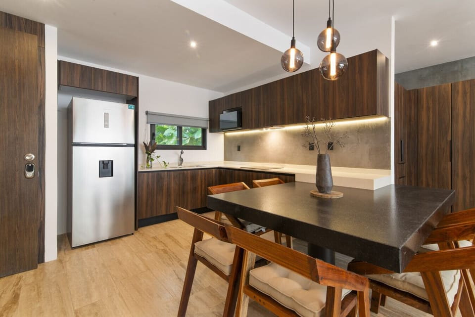 Sleek kitchen with wood cabinets, black table & warm lighting.