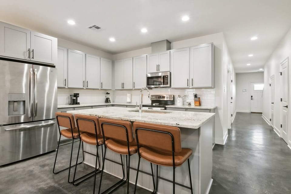 This open-concept kitchen is designed for both style and functionality. A spacious island with barstool seating serves as the centerpiece, offering the perfect spot for casual dining or entertaining.