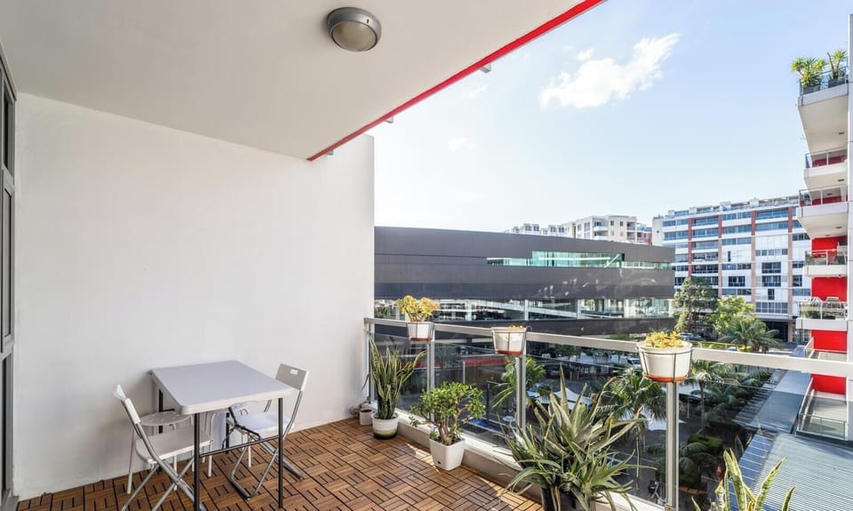 A cozy outdoor balcony furnished with a small table and chairs, offering an elevated view of the urban surroundings.