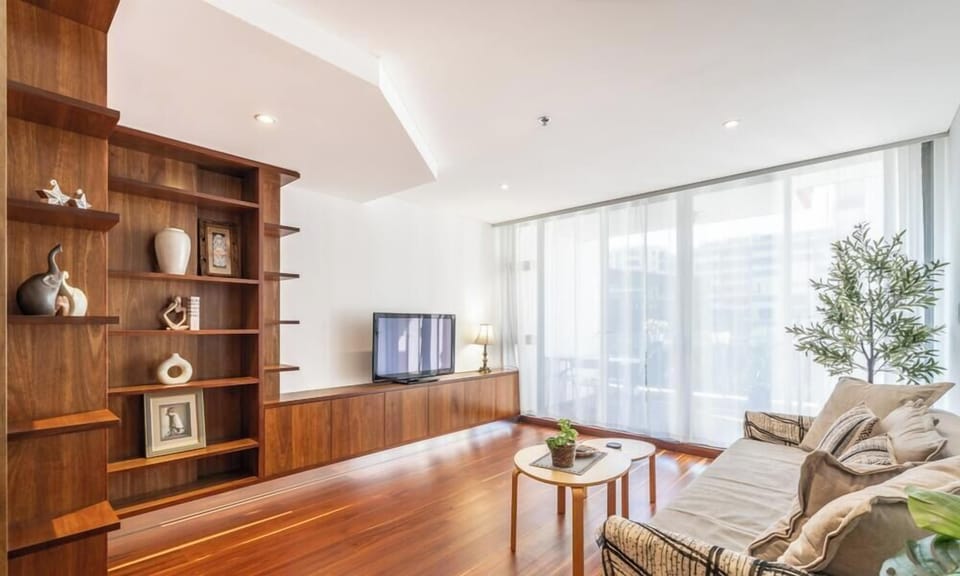 A modern living area featuring wooden shelving, a comfortable sofa, and hardwood flooring.