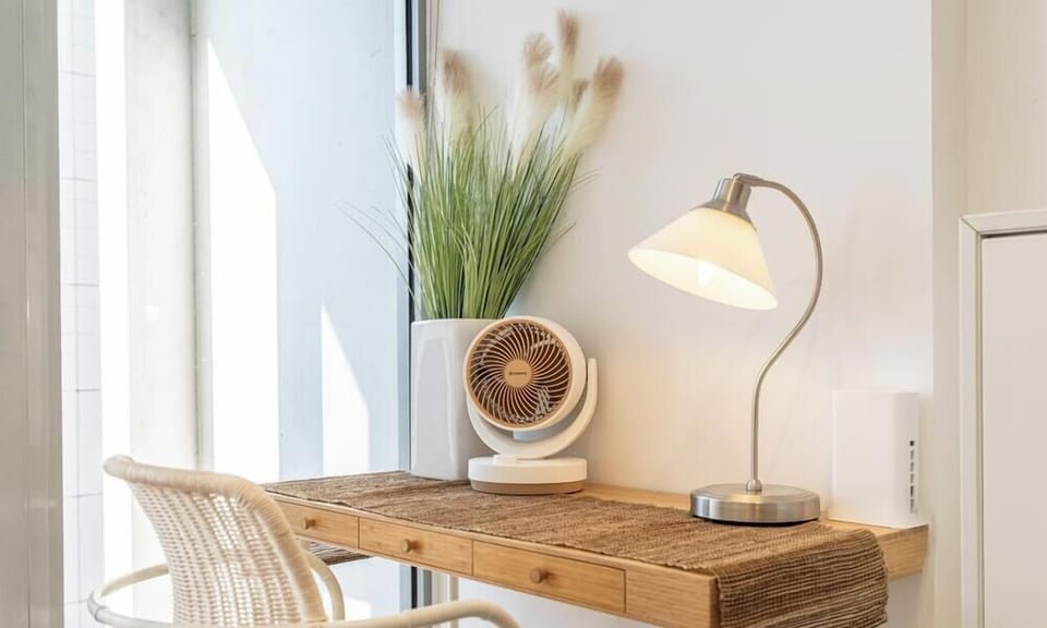 A functional corner setup with a desk, lamp, and indoor plants.