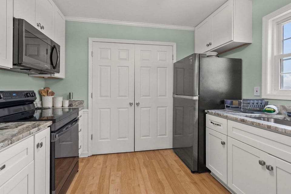Full kitchen with white cabinets, a range and a window above the sink at Endless Summer in Cherry Grove