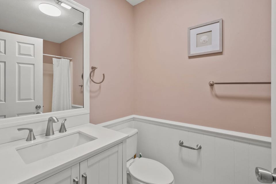 Pink-walled bathroom with a white vanity and grab bar at Endless Summer, a Cherry Grove rental