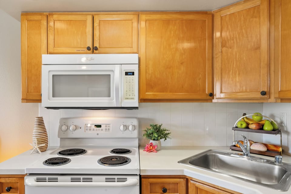 Kitchen layout with wooden cabinets, white appliances and tiled surfaces, neatly arranged accessories and framed artwork enhancing the design.