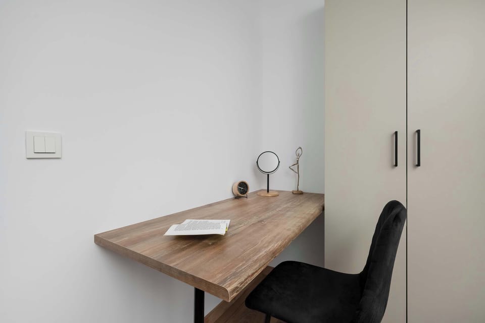 A small desk with a chair placed in the corner of a room. Ideal for working remotely.