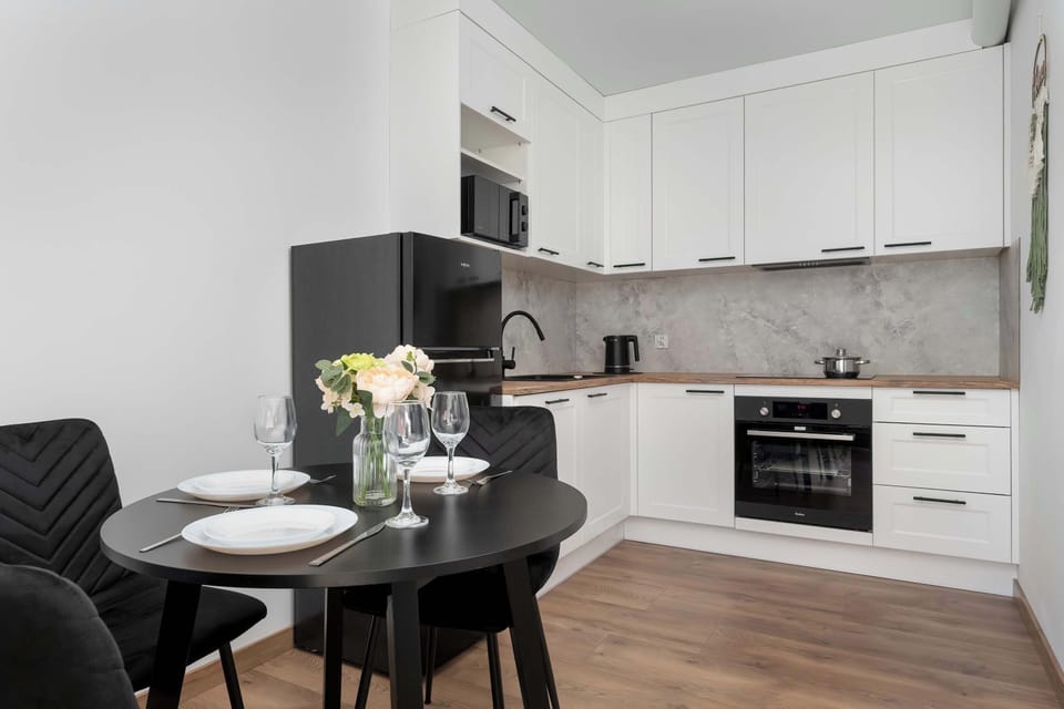 A compact kitchen with white cabinets, oven, and gray backsplash. Functional design for everyday cooking.