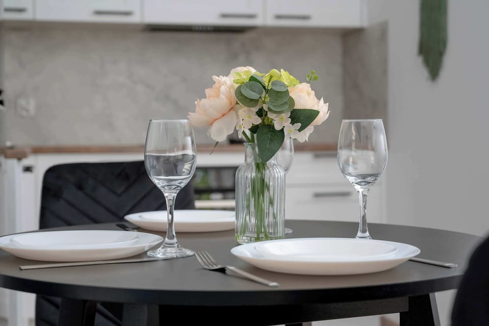 A dining table set for two with wine glasses and flowers. A romantic touch in the apartment.