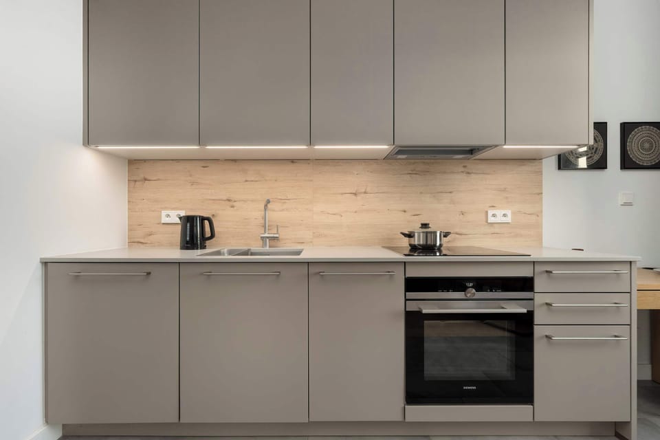 A sleek gray kitchen with built-in appliances and wooden countertop.
