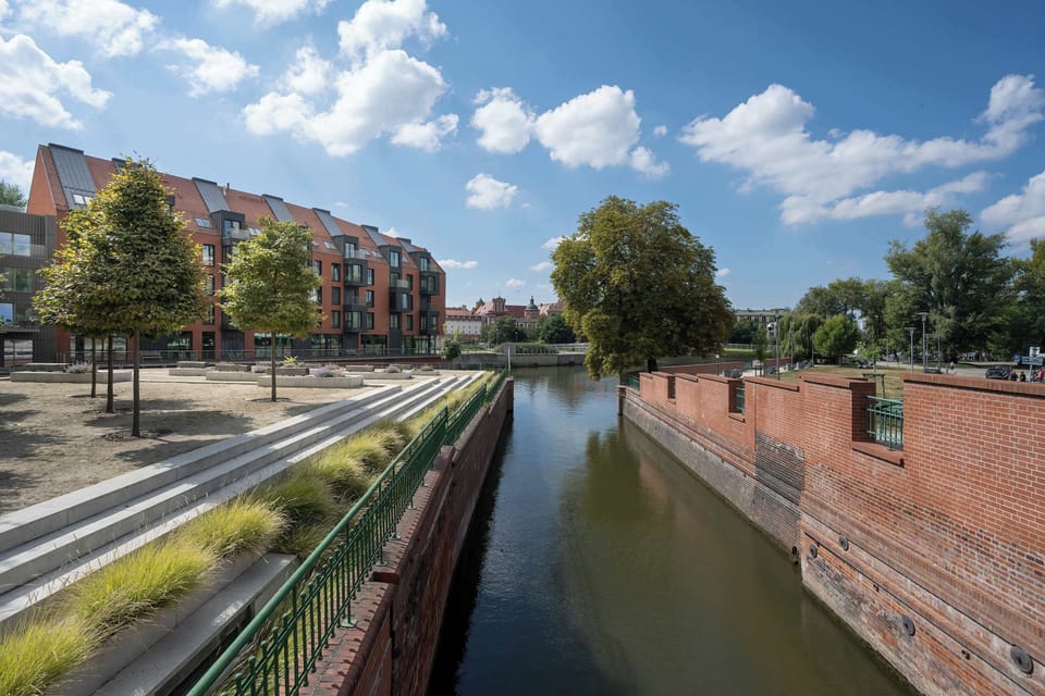 A scenic riverside walkway lined with red brick walls and trees.
