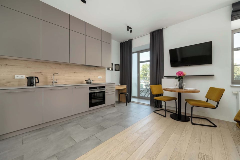 A compact kitchen with light cabinetry, modern appliances, and a dining table.