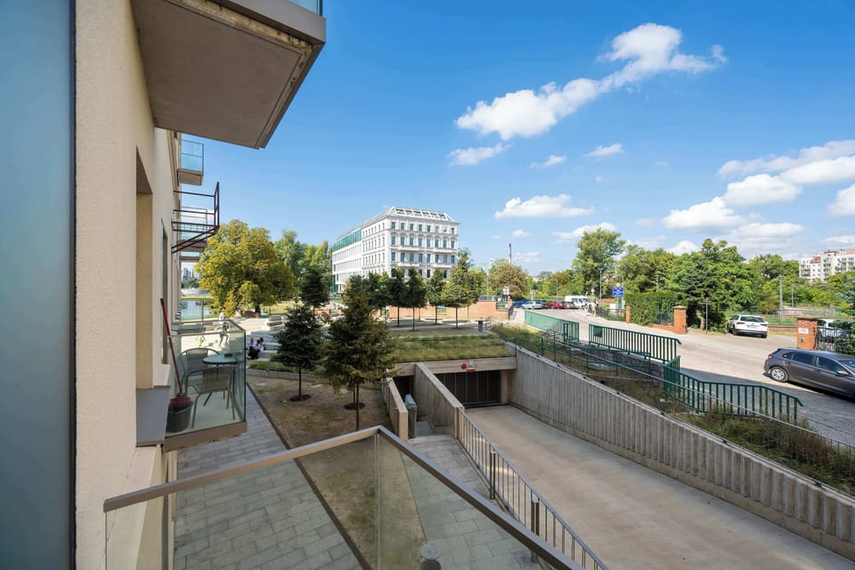 A balcony overlooking a peaceful street with greenery and parked cars.