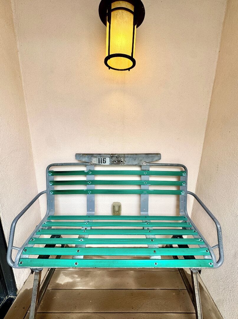 A charming vintage-style bench awaits at the entrance, offering you a welcoming spot to pause and settle in. The warm overhead lighting adds a cozy glow to your arrival.